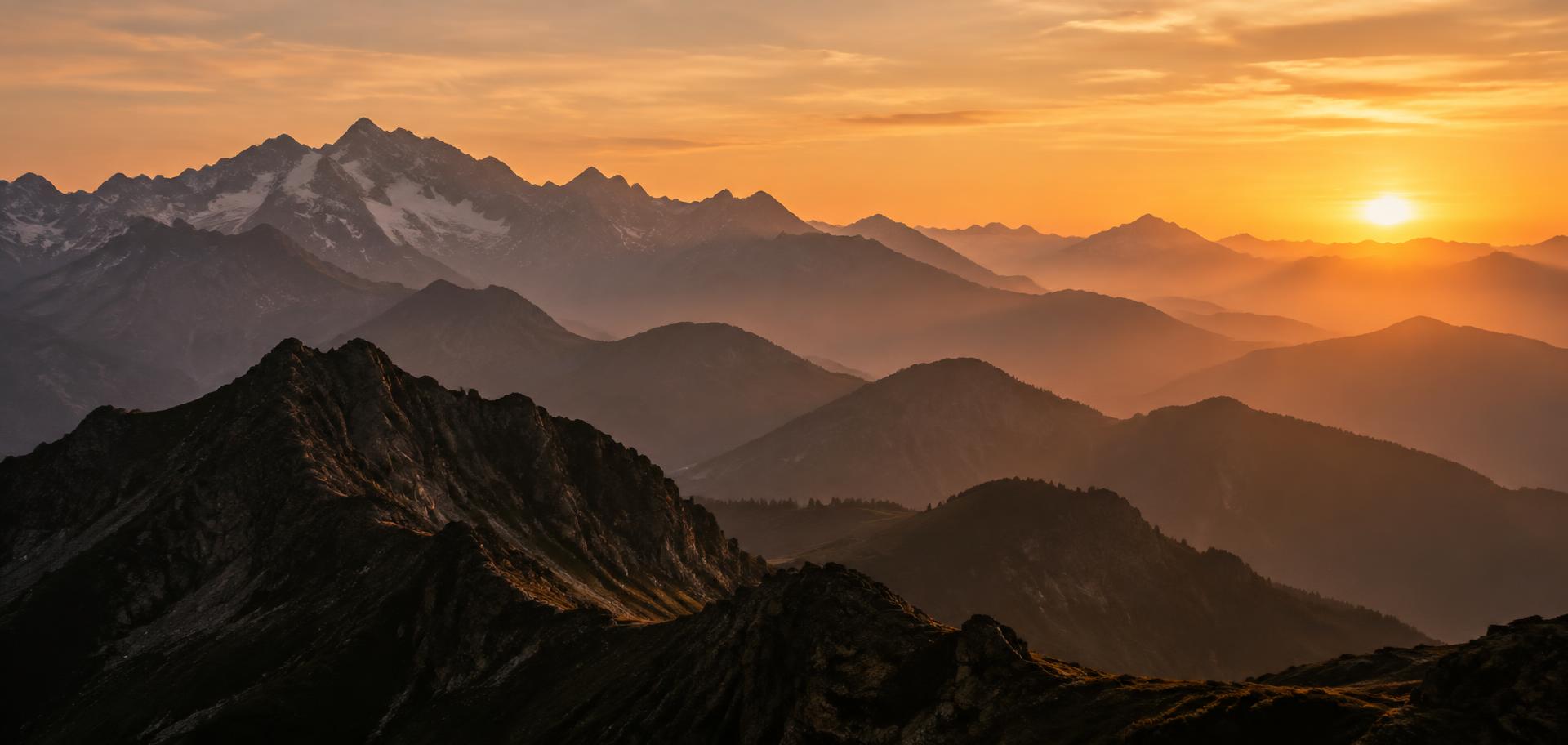 Cadena de montañas al atardecer con capas de luz cálida